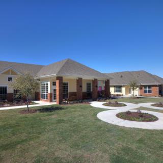 A modern residential building with well-maintained lawns and pathways under a clear blue sky.