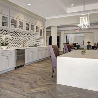 A modern kitchen with white cabinetry, a large island, and herringbone flooring.
