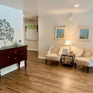 A cozy living room with wood flooring, comfortable seating, and decorative artwork.