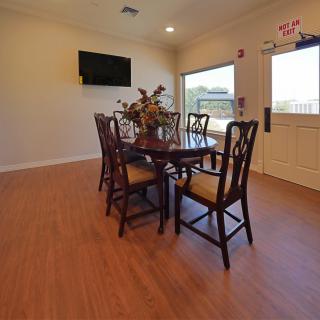 A cozy dining room with a wooden table, chairs, and a wall-mounted television.