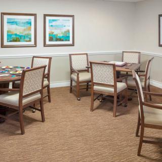 A neatly arranged dining room with tables and chairs, featuring artwork on the walls.