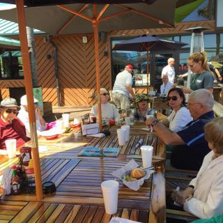A group of people enjoying a meal together on a sunny patio.