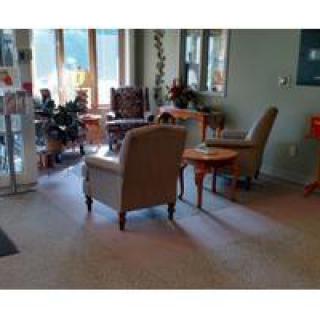 A cozy waiting room area with chairs and a table, illuminated by daylight through the windows.