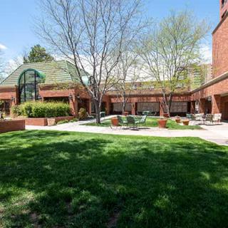 A view of a brick building with a green lawn and trees on a sunny day.