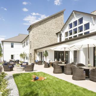 A sunny outdoor patio area with comfortable seating, umbrellas, and a well-maintained lawn.