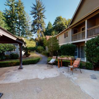 A peaceful outdoor area with chairs and a table surrounded by houses and lush greenery.