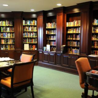 A cozy library space featuring elegant wooden bookshelves filled with books and comfortable seating.
