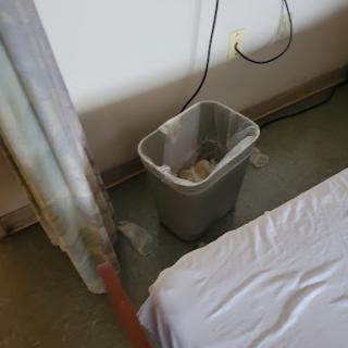 A view of a hospital room featuring a trash can beside a bed.