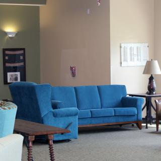 A cozy living room with a blue sofa and wooden furniture.