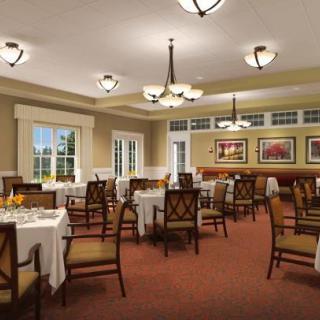 An elegant dining room with neatly arranged tables and chairs, featuring decorative chandeliers and artwork on the walls.