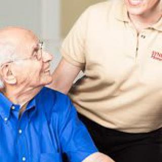 A caregiver assists an elderly man, showing friendly interaction.