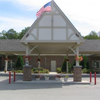 The welcoming entrance of a building adorned with an American flag and well-maintained landscaping.