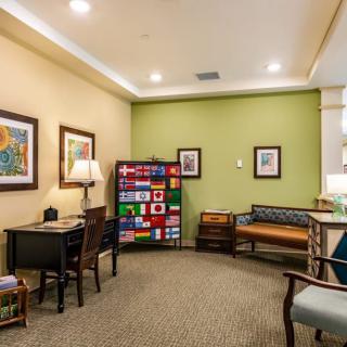 A cozy waiting room featuring comfortable seating, artwork on the walls, and a lamp for ambient lighting.