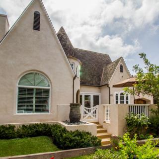 Charming cottage-style house with well-maintained garden and lush greenery.