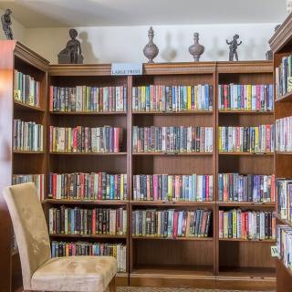 A cozy reading corner featuring a large wooden bookshelf filled with a variety of books and decorative items.