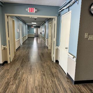 A well-lit corridor featuring multiple doors along the sides and a polished wooden floor.