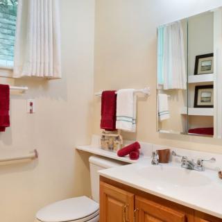 A well-decorated bathroom featuring a sink, mirror, toilet, and red towels.
