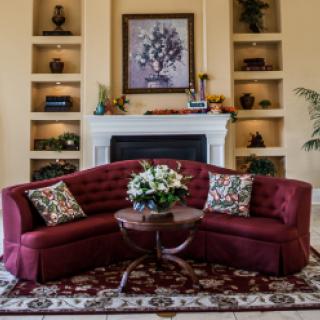 A cozy living room with a red sofa, floral centerpiece, and elegant fireplace surrounded by built-in shelves.