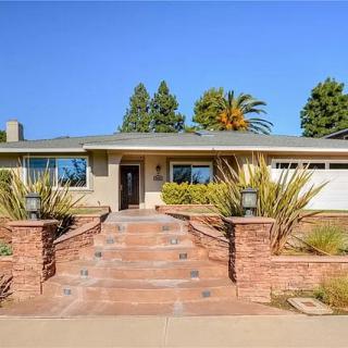 A well-maintained single-story house with a landscaped front yard and palm trees in the background.