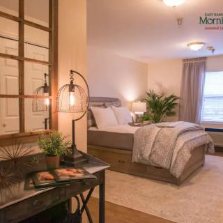 A cozy and modern bedroom with neutral colors, featuring a comfortable bed, stylish lighting, and greenery.