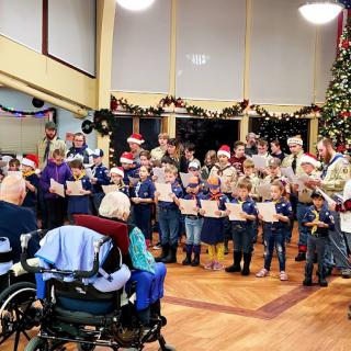 A group of children sings Christmas carols for seniors at a holiday event.