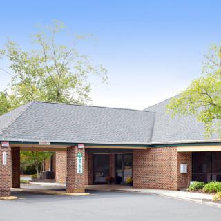 A brick medical clinic with a drive-thru area surrounded by trees.