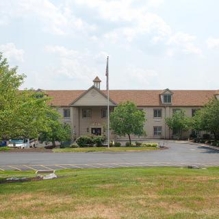 A hotel building with a parking lot and surrounding trees.