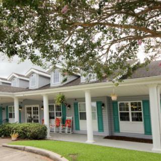 A charming residential building with a porch surrounded by greenery.