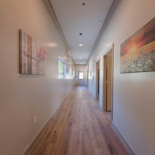 A well-lit hallway adorned with artwork, featuring a wooden floor and inviting ambiance.