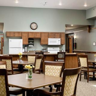 A cozy kitchen and dining area featuring several tables and chairs with wooden cabinetry and appliances.