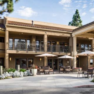 A two-story building with outdoor seating and umbrellas on a sunny day.