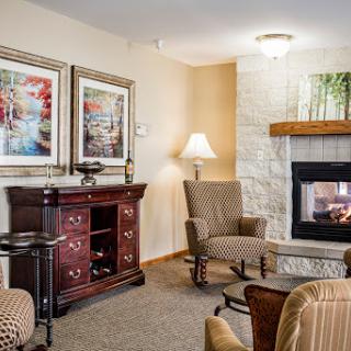 A cozy living room featuring a fireplace, comfortable seating, and decorative artwork.