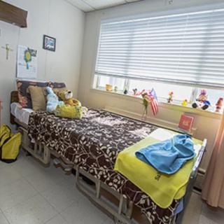 A well-decorated hospital room with a bed, window, and colorful decorations.
