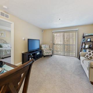 A cozy living room featuring a television, comfortable seating, and a dining area.