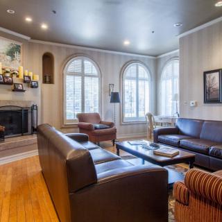 A cozy living room featuring leather sofas, a fireplace, and large arched windows.