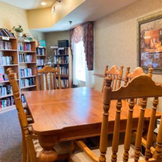 A cozy library room featuring wooden furniture and filled bookshelves.