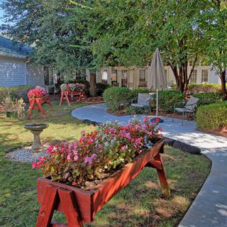 A serene garden with vibrant flowers, a winding pathway, and cozy patio seating.