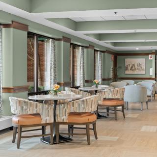 A modern dining area with tables and chairs, featuring large windows and elegant decor.
