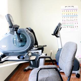 A small gym setup with stationary bikes and chairs.