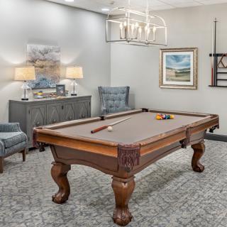 A stylish recreation room featuring a pool table, elegant lighting, and tasteful decor.