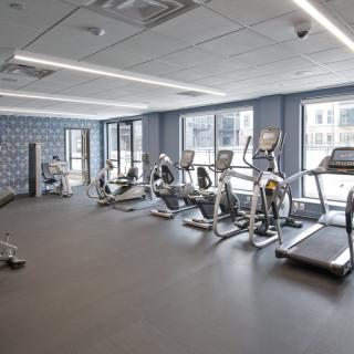 A modern gym with various cardio equipment, including treadmills and stationary bikes.