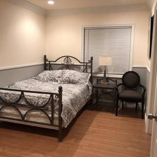 Cozy bedroom with a metal bed frame, patterned bedding, and a lamp on the nightstand.