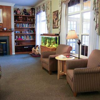 A cozy living room with armchairs, a fireplace, and a fish tank near the window.