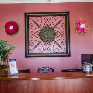 A reception area with a decorative wall piece and flower arrangements.