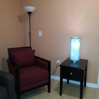 A cozy corner featuring a comfortable chair, a side table with a glowing lamp, and a floor lamp.
