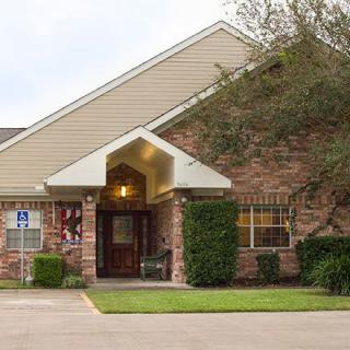 A front view of a brick building with an entrance and surrounding greenery.