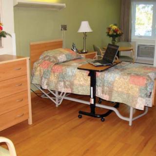 A hospital room with a bed, side table, and medical equipment.