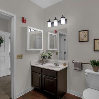 A modern bathroom with a vanity, mirror, and stylish light fixture.
