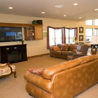 A cozy and modern living room featuring leather seating, a television, and ample natural light.