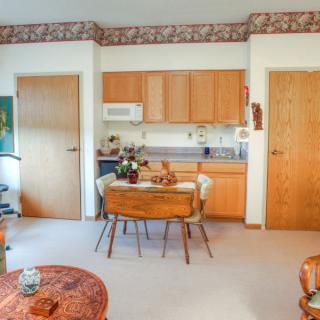 A cozy kitchen and dining area with wooden cabinets and a small table set for two.